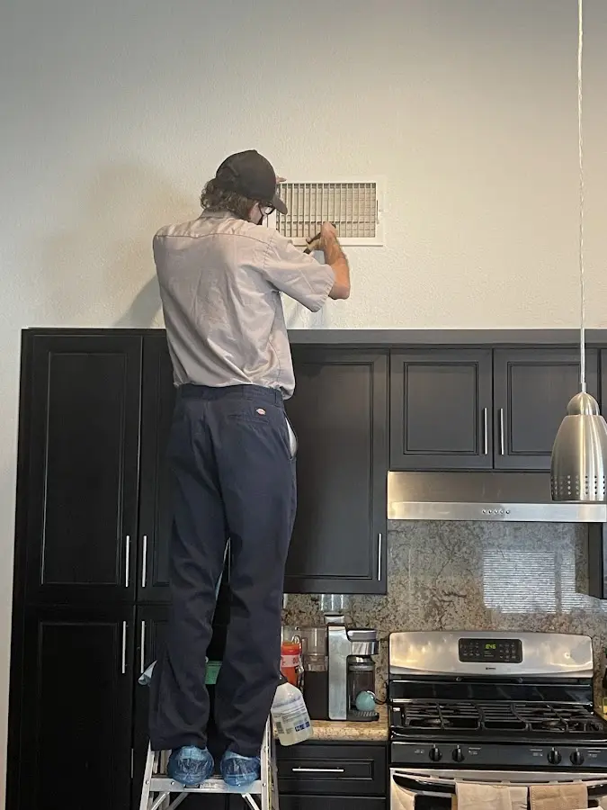 Technician inspecting an air vent during HVAC service in North Kansas City